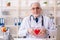 The aged male doctor cardiologist with heart model