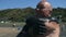 An aged man applies black healing mud to his body on a salt water lake. Black mud, clay is useful for people with health