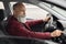 Aged man driver turning on music in car before moving