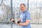 Aged man exercise with dumbbells near window