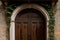 An aged oak door adorned with a crown of ivy