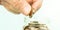 Aged person hand puts golden coin into glass jar closeup