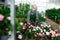 Aged saleswoman arranging potted blooming azaleas in garden shop