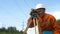 Aged surveyor looks through dumpy level under power lines