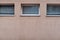 Aged weathered pink wall with three windows with blinds texture detail urban sighing with lots of copy space for text