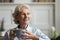 Aged woman enjoy hot beverage resting on sofa at home