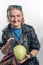 A aged woman, in a leather jacket, takes out cabbage from her bag.  Crazy and surprised with a smile. Old model in studio