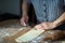 Aged woman`s hands making casadielles at home. Homemade dough, wooden roller pin and a knife. Gastronomy