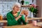 Aged woman tenderly palming photo frame while sitting at table