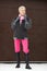 Aged woman winter outfit with high boots, pink pants, bomber jacket, stylish full length look of mature female with short hair,