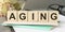 Ageing - word from wooden blocks with letters, growing old senescence ageing concept, random letters around