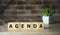 AGENDA word made with building blocks on brick background.