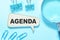 Agenda the word is written on a wooden pop-up box on a blue background