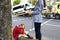 An agent fills out documents after car accident, driver sits nearby and holds his head with his hands