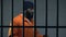 Aggressive afro-american prisoner in camera holding cell bars, life sentence