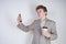 Aggressive caucasian teenager screams into the smart phone and holds a paper cup of coffee in his hand. student on edge on a white