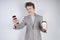 Aggressive caucasian teenager screams into the smart phone and holds a paper cup of coffee in his hand. student on edge on a white