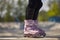 Aggressive inline skater girl wearing purple skates. Feet of female roller blader in outdoor skatepark in summer