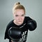 Aggressive teenager girl with box gloves on the grey background