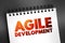 Agile Development - any development process that is aligned with the concepts of the agile manifesto, text concept on notepad