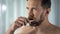 Aging man brushing teeth and looking at mirror, morning procedure, dental care