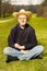 Aging man resting on sunny park grass in dark shirt and hat