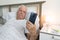 Aging senior man male sick ill alone retired resting virus holding smartphone