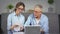 An agitated elderly couple checks unpaid debts on a laptop and gets upset.