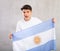 Agitated sports male fan holds canvas of national flag of Argentina in hands and chants slogan