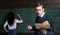 Agitated young teacher with anxious look standing in the classroom with book and chalk in his hands. Young student