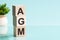 AGM - Annual general meeting - acronym on wooden cubes on blue backround. Business concept