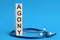 Agony word written on wooden blocks and stethoscope on light blue background