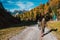 Agordo, Italy - 24 october 2018: couple of young explorer photographer walking in mountain path with scenic landscape and forest