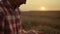 Agrarian man worker analyzing grains at sunrise wheat field. Harvest concept