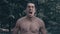 Agressive man with a naked torso furiously screaming in the forest