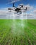 Agricultural drone sprays rows of winter wheat sprouts on a background of beautiful sky,modern agriculture