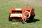 Agricultural farming haymaking equipment left in local field after heavy usage surrounded with green grass