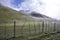 Agricultural fence. Green hills with descending fog. Kyrgyzstan Tien Shan