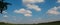 Agricultural field and forest sky with clouds, panorama. Autumn season in the countryside