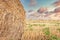 Agricultural field after harvest, straw rolls, straw bale on farmer field and dramatic cloudy sky in late afternoon