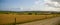 Agricultural fields of Ireland under the blue sky on a summer evening. A country road near a fenced field