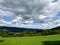 Agricultural grass landscape in hills of europe. Wide view with clouds.