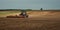 agricultural industrial landscape. a modern tractor with a trailed cultivator works on a hilly field before the autumn sowing