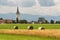 Agricultural land and small village with a church, Austrian Alps in the background