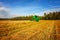 Agricultural landscape. Combine harvesting grain in a field against a blue sky.