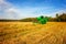 Agricultural landscape. Combine harvesting grain in a field against a blue sky.