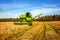 Agricultural landscape. Combine harvesting grain in a field against a blue sky.