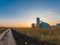 Agricultural landscape. Grain storage station, shiny metal grain tanks in the field. Sunset
