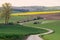 Agricultural landscape with tractor plowing a striped brown field in South Moravia