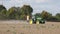 Agricultural machine spray stubble field near autumn trees. 4K